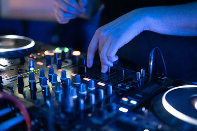 Midsection of dj playing music at club