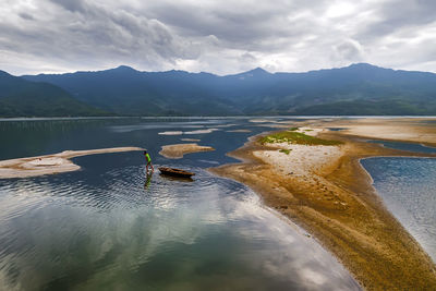 Scenic view of lake by mountains against sky