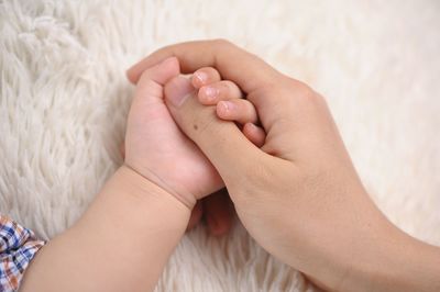 Copped image man holding toddler hand