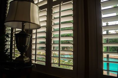 Close-up of electric lamp on table by window