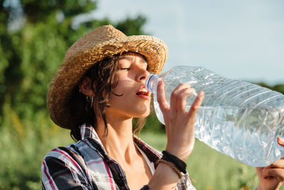 Close-up of young woman drinking water standing outdoors