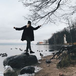 Woman standing on rock against sky