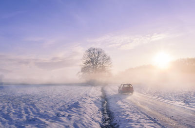 Scenic view of snow covered road  at sunrise