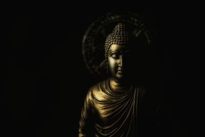 Close-up of buddha statue against black background