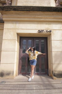 Full length of woman standing at entrance of building