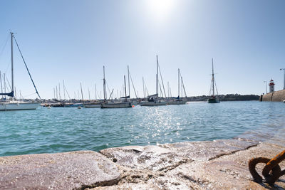 Sailboats sailing in sea against clear sky