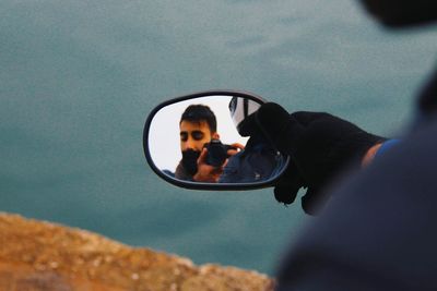 Reflection of man photographing on car