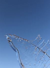 Low angle view of icicles against clear blue sky