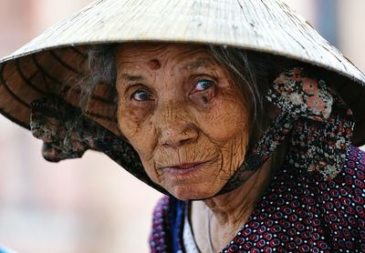 Portrait of senior woman wearing hat sitting against blurred background