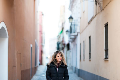 Young woman standing amidst buildings in city