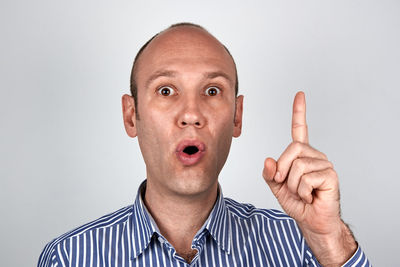 Portrait of mature man with raised eyebrows against gray background