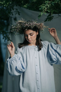 Young woman looking away while standing against plants