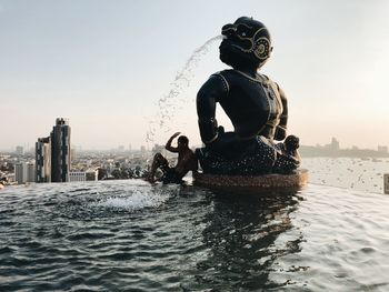 Man sitting by sculpture in infinity pool