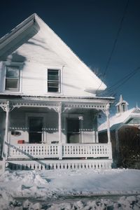 Low angle view of house on snow covered field against sky