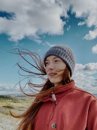 Portrait of smiling woman standing on land against sky