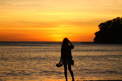 Silhouette of woman on beach at sunset