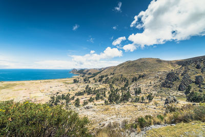 Scenic view of landscape by sea against sky