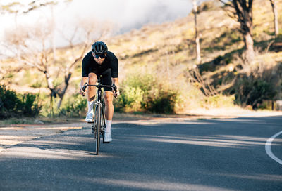 Rear view of man riding bicycle on road