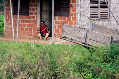 Portrait of man sitting on brick wall