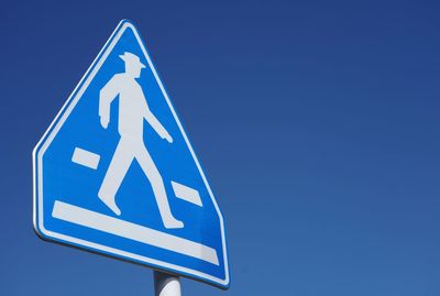 Low angle view of road sign against clear blue sky