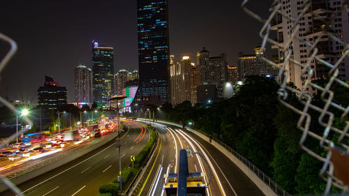 Light trails on road amidst buildings in city at night