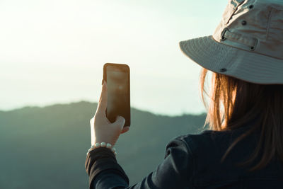 Rear view of woman photographing against clear sky