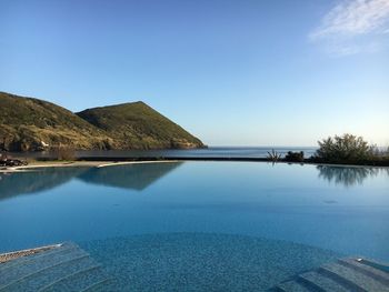 Scenic view of swimming pool by lake against sky