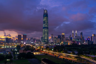 Illuminated modern buildings in city against sky