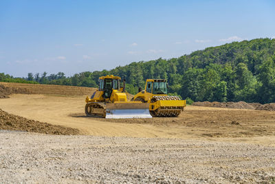 Bulldozer and roller compactor side by side on a building lot,