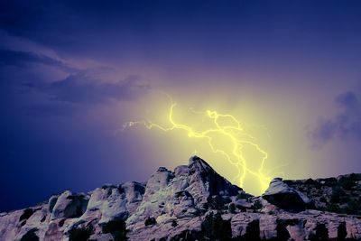 Low angle view of lightning over mountain against sky