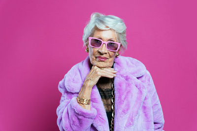 Portrait of woman wearing sunglasses while standing against yellow background