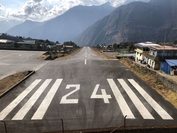 Road by mountains against sky in city