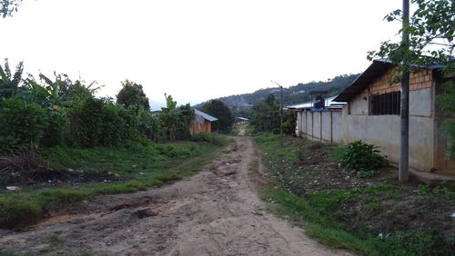 Road amidst houses against clear sky