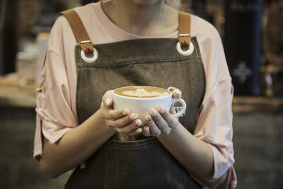 Midsection of man holding coffee cup