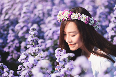 Close-up of woman with pink flowers against blurred background