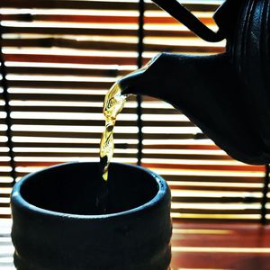 Close-up of hand pouring tea cup