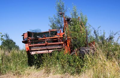 Abandoned truck on field against clear blue sky