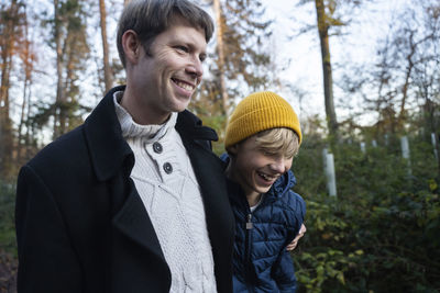 Happy father and son walking in autumn forest