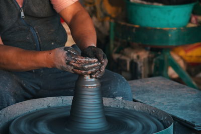 Midsection of professional potter making bowl in pottery workshop - kathmandu, nepal