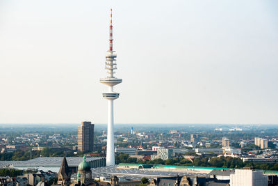 Communications tower in city against clear sky