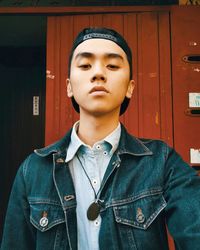 Close-up portrait of serious young man wearing denim jacket