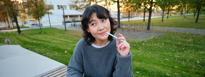 Young woman blowing bubbles while standing against trees