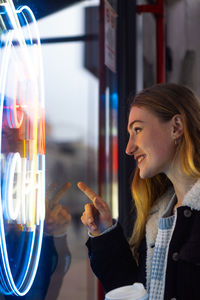 Side view of young woman against window of shop