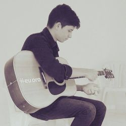 Young man playing guitar against white background