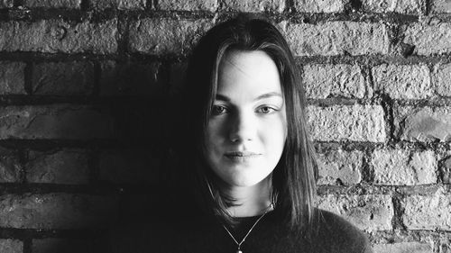 Portrait of young woman standing against wall