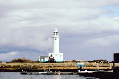 Lighthouse by sea against sky