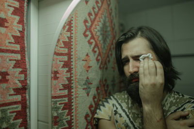 Close-up of man crying while reflecting on mirror at home