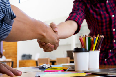 Midsection of couple holding hands at table