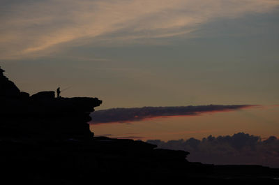 Silhouette rock formations against sky during sunset