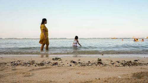 People on beach against clear sky